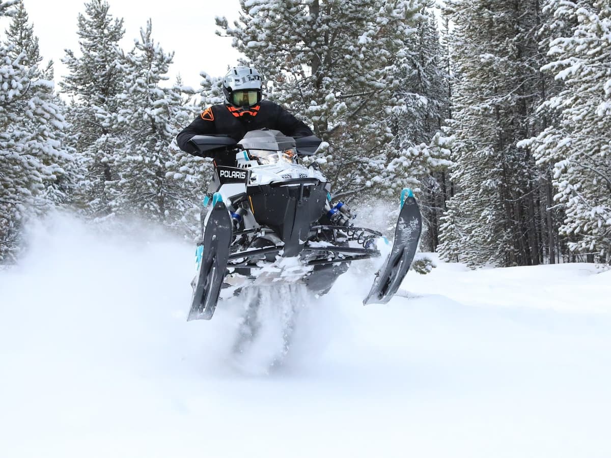A person driving a Switchback Assault 2025 snowmobile in the snow