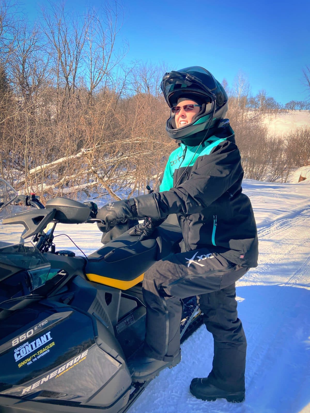 a woman wearing the ckx alaska clothing set stepping on her snowmobile