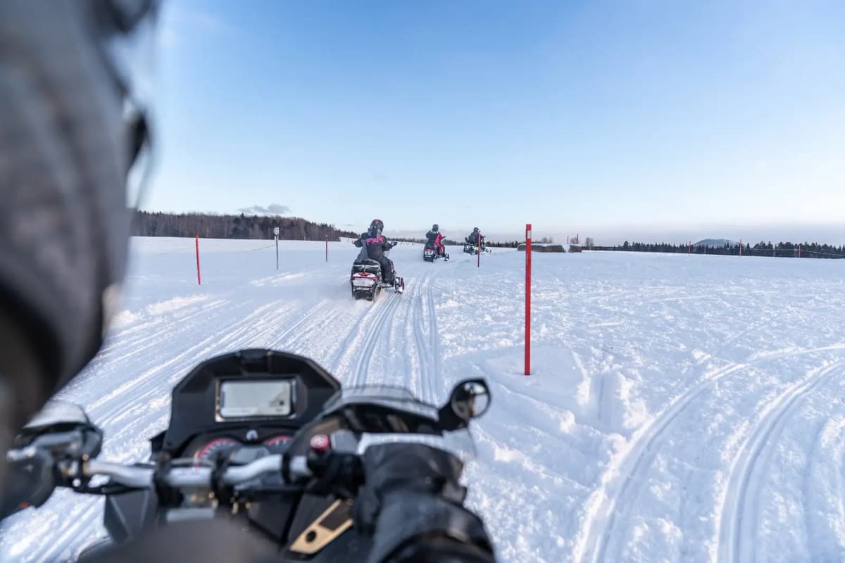 First-person view of a group of snowmobilers riding on a snow-covered trail in Québec.