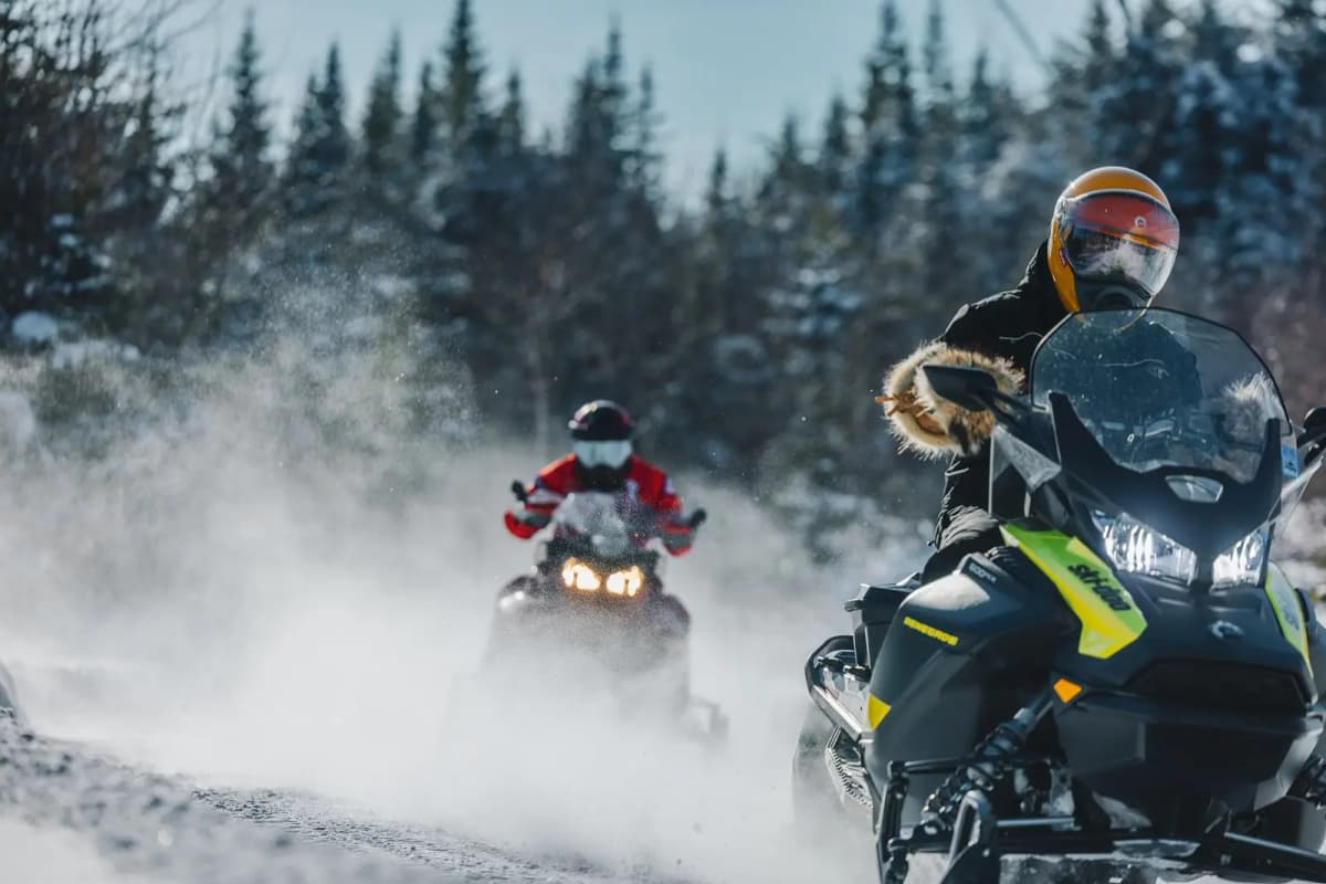 Two snowmobilers riding on a snowy trail in the Lanaudière region, nicknamed the Snowmobile Country.